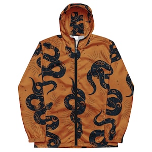 Op de afbeelding: Een hooded jack met een ritssluiting en lange mouwen. De jas is oranje met een zwart en gouden slangpatroon. Het slangpatroon bevat sterren en manen.