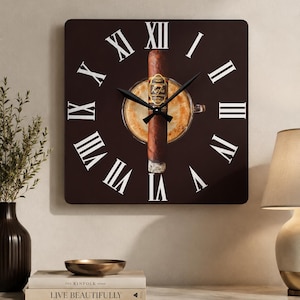 May include: A square wall clock with a dark brown background featuring white Roman numerals. The center displays a graphic of a coffee cup and a cigar with the text Kafie. The clock has two black hands indicating the time against the dark face.