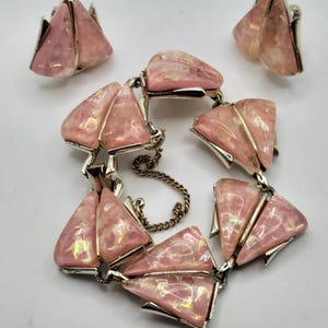 May include: A vintage jewellery set comprising a bracelet and matching clip-on earrings. The set features a pink, iridescent, triangular design with silver-tone metal accents. The bracelet has a safety chain.