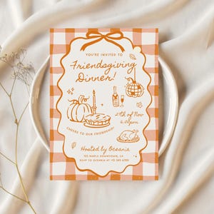 May include: A rectangular Friendsgiving dinner invitation card featuring an orange and white gingham background. The center has a scalloped frame with a bow, containing line art of a pumpkin, pie, bottle, disco ball, and turkey with text.