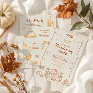 May include: Two cream-colored invitation cards with orange text and illustrations for a Friendsgiving party. One card lists menu details, the other invites guests. Autumn leaves and a small pumpkin decorate the scene.