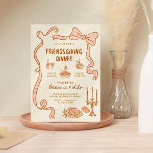 May include: A Friendsgiving dinner invitation on cream-colored paper with orange illustrations and text. The invitation includes a bow, ribbon, and illustrations of food and drinks. The text reads "Join us for a Friendsgiving Dinner" and includes the date, time, and location.