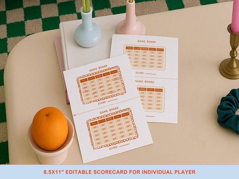 Op de afbeelding: Witte spelscorecards met een oranje rand en een rasterindeling. De kaarten hebben de tekst "GAME BOARD" en "SCORE:" erop gedrukt. Een sinaasappel ligt in een kleine witte kom. De tekst "8.5x11" EDITABLE SCORECARD FOR INDIVIDUAL PLAYER" staat onderaan.