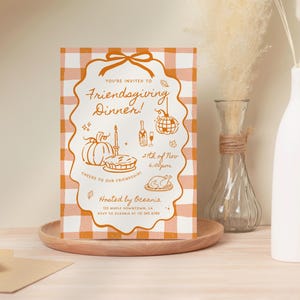 May include: A rectangular Friendsgiving dinner invitation card with an orange and white gingham pattern. The card features orange line art of a pumpkin, pie, candle, wine bottle, disco ball, and turkey with text including 21st of Nov 6:00pm.