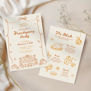 May include: Two cream-colored Friendsgiving party invitations with orange illustrations and text. One invitation reads "Join us for a Friendsgiving Party" and includes details. The other lists menu details. The invitations are on a cream-colored surface.