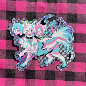 May include: A holographic sticker featuring a three-headed creature with a pink, blue and white colour scheme. The creature has a wolf-like body with a human-like head and a heart-shaped pendant around its neck.