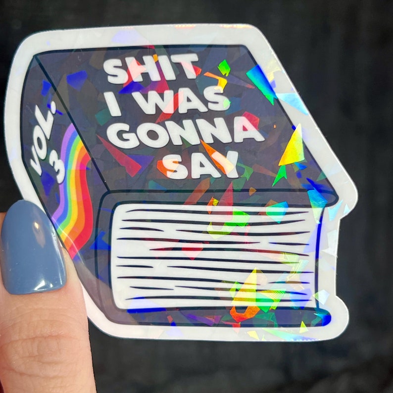 K&ouml;nnte beinhalten: Ein holografischer Aufkleber eines Buches mit dem Text "SHIT I WAS GONNA SAY" und "VOL. 3" auf dem Cover.