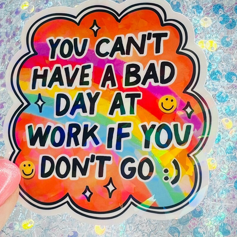 Puede incluir: Una colorida pegatina con el texto "YOU CAN'T HAVE A BAD DAY AT WORK IF YOU DON'T GO :) ". La pegatina tiene un fondo de arco&iacute;ris y un borde blanco en forma de nube con ribete negro. Incluye emoticonos y estrellas.