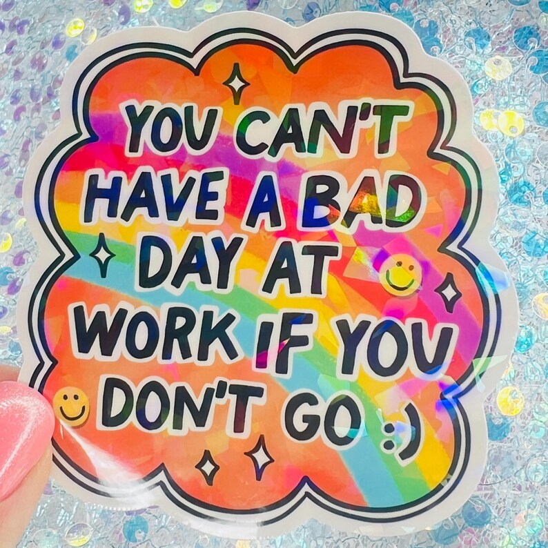 Puede incluir: Una colorida pegatina con un borde en forma de nube. La pegatina presenta el texto "YOU CAN'T HAVE A BAD DAY AT WORK IF YOU DON'T GO :)" en una fuente divertida, con un fondo de arco&iacute;ris y detalles de estrellas y emoticonos.