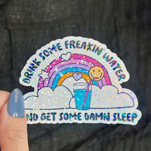 May include: A white sticker with a rainbow, a glass of water with a straw, and the text "Drink some freakin' water and get some damn sleep".