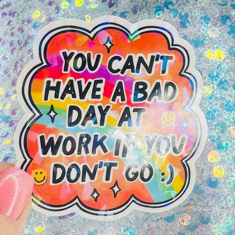 Puede incluir: Una pegatina colorida con el texto "YOU CAN'T HAVE A BAD DAY AT WORK IF YOU DON'T GO :) ". La pegatina tiene un borde blanco y un fondo de arco&iacute;ris. Incluye una carita sonriente y estrellas.