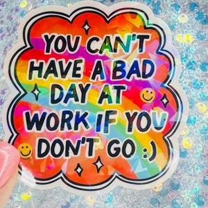 May include: A colorful sticker with the text "YOU CAN'T HAVE A BAD DAY AT WORK IF YOU DON'T GO :) ". The sticker has a rainbow gradient background and a black outline. The sticker also has a smiley face and star graphics.