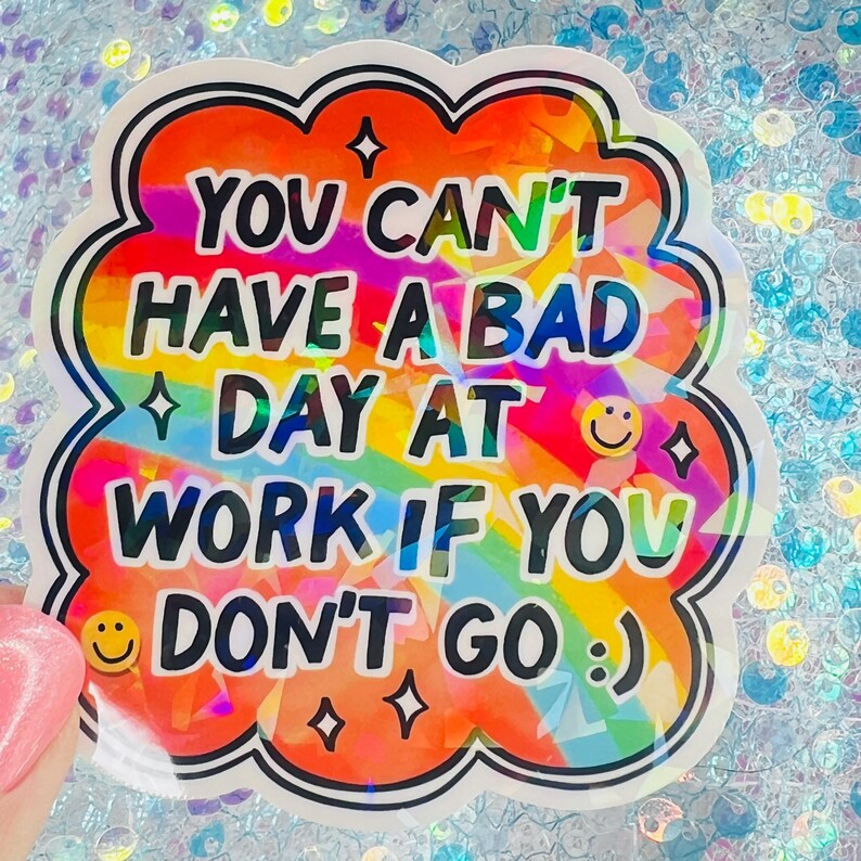 Puede incluir: Una colorida pegatina con un fondo de arco&iacute;ris y el texto "YOU CAN'T HAVE A BAD DAY AT WORK IF YOU DON'T GO :) ". La pegatina tiene un borde blanco y negro con estrellas y emoticonos.