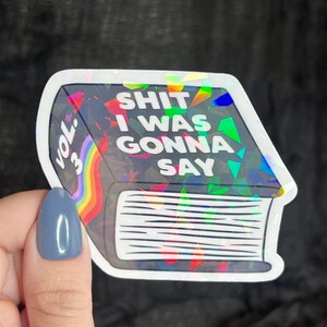 K&ouml;nnte beinhalten: Ein holografischer Aufkleber eines Buches mit dem Text "SHIT I WAS GONNA SAY" und "VOL. 3" auf dem Cover.