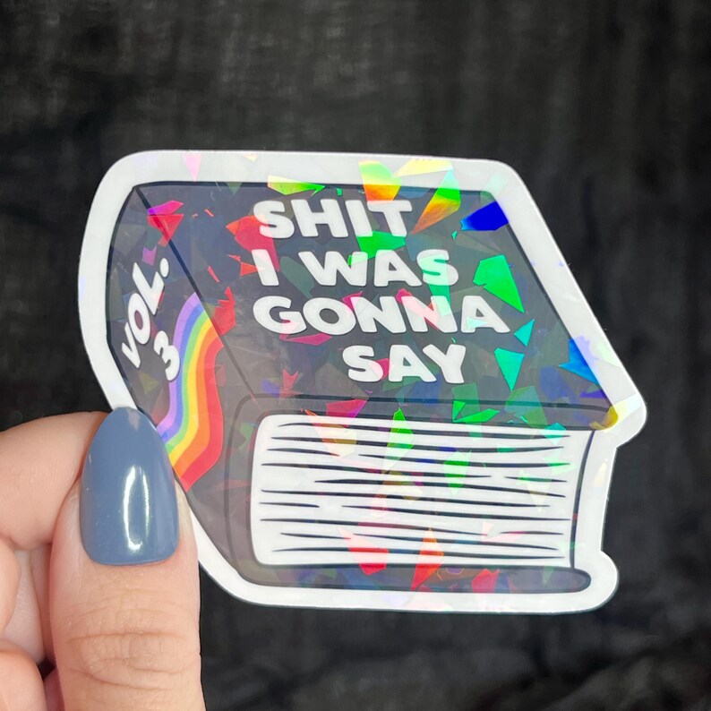 K&ouml;nnte beinhalten: Ein holografischer Aufkleber eines Buches mit dem Text "SHIT I WAS GONNA SAY" und "VOL. 3" auf dem Cover.
