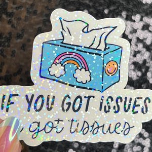 May include: A white sticker with a blue tissue box with a rainbow and a smiley face. The text on the sticker reads "If you got issues, got tissues".