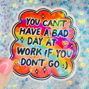 Puede incluir: Una colorida pegatina con el texto "YOU CAN'T HAVE A BAD DAY AT WORK IF YOU DON'T GO :) ". La pegatina tiene un fondo de arco&iacute;ris y un borde blanco con forma de nube. Incluye caras sonrientes y estrellas.