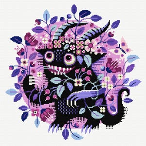Op de afbeelding: Een kruissteekontwerp met een zwart monster met hoorns, grote ogen en een grijnzende mond, versierd met een bloemenkrans en omgeven door paarse en roze bloemen en bladeren. Er is ook een vlinder aanwezig.