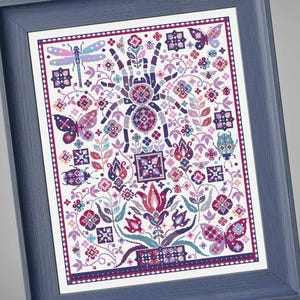 May include: Cross-stitch artwork in a blue frame. The design features a central tarantula surrounded by butterflies, flowers, and insects in shades of purple, pink, and teal. The artwork has a detailed, folk-art style.