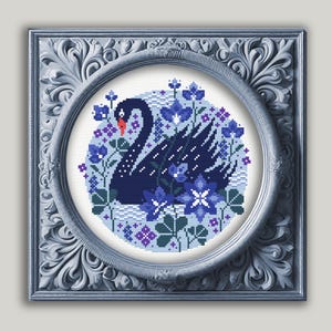 May include: A black swan with a long neck and a white beak surrounded by blue and purple flowers on a white background. The swan is in a circular frame with a blue and white border.