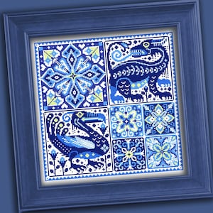 May include: A square cross-stitch embroidery framed in a blue wooden border. The design features a grid of six panels with blue, white, and light green geometric patterns, a stylised dragon, and a large bird, all rendered in intricate needlework.
