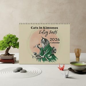 A spiral-bound wall calendar titled "Cats in Kimonos Eating Sushi 2026 Calendar" features an illustration of a cat in a green kimono eating sushi with chopsticks.