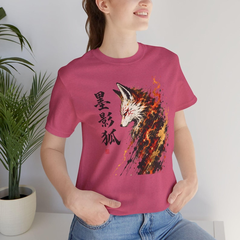 A woman models a dark pink t-shirt with a graphic of a fox head with red and orange flames and black Japanese characters on the left side.
