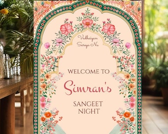 May include: A floral-themed welcome sign for a Sangeet Night, featuring a peach background with green and gold accents. The sign reads "Welcome to Simran's Sangeet Night" with the name "Simran's" in a larger, decorative font. The sign is decorated with colorful flowers and intricate patterns.
