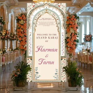May include: A wedding sign with an ornate floral design and a gold frame. The sign reads "Welcome to the Anand Karaj of Harman & Taran".
