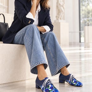 Women wearing blue floral Oxford shoes in a seated fashion editorial look.