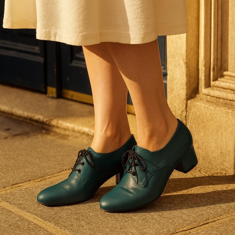 Handmade teal leather Oxford shoes with 3cm heel, photographed in soft daylight on Parisian sidewalk.