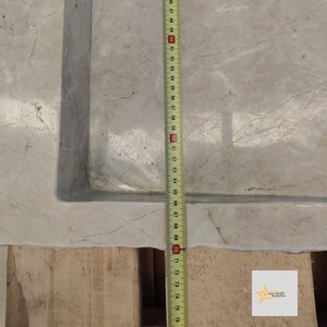 May include: A close-up of a white marble sink with a measuring tape beside it. The tape measures 76 centimeters.