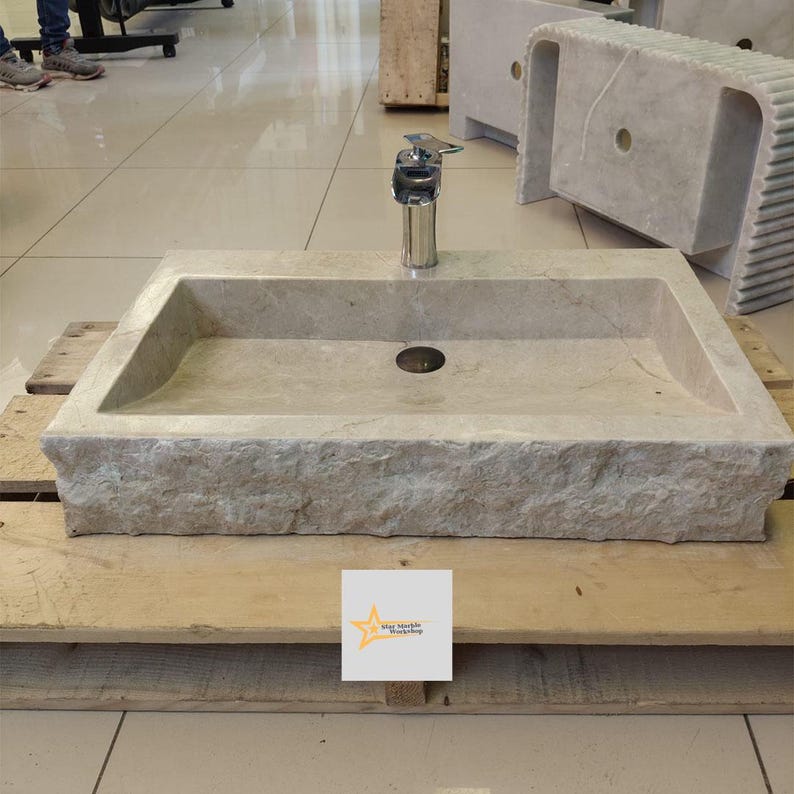 May include: A rectangular stone sink with a rough-hewn edge and a single faucet. The sink is sitting on a wooden pallet.