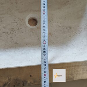 May include: A light beige stone sink with a circular drain hole. A measuring tape shows the sink's length, marked from 16 to 43 inches. The sink has a smooth, polished surface. The logo of "Star Marble Workshop" is in the bottom right corner.