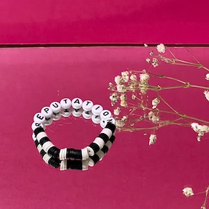 May include: A black and white beaded bracelet with the word "REPUTATION" spelled out in black letters on white beads.