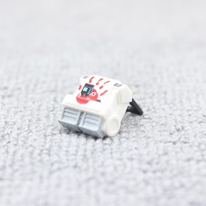 May include: White toy robot with red handprint design and a black handle. The robot has two gray compartments on the bottom.