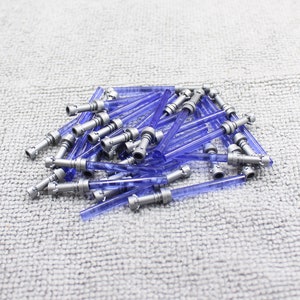 May include: A pile of blue lightsaber toy parts for Lego minifigures. The lightsaber blades are translucent blue and the handles are silver.