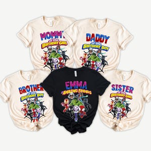 Puede incluir: Cinco camisetas con gr&aacute;ficos de superh&eacute;roes. Las camisetas son crema y negras, con textos que dicen "Mommy of the Birthday Girl", "Daddy of the Birthday Boy", "Brother of the Birthday Boy", "Emma Amazing Friends" y "Sister of the Birthday Girl".