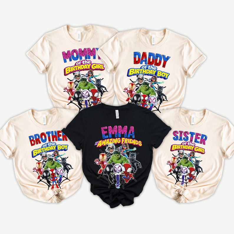 Puede incluir: Cinco camisetas con gr&aacute;ficos de superh&eacute;roes. Las camisetas son crema y negras, con textos que dicen "Mommy of the Birthday Girl", "Daddy of the Birthday Boy", "Brother of the Birthday Boy", "Emma Amazing Friends" y "Sister of the Birthday Girl".