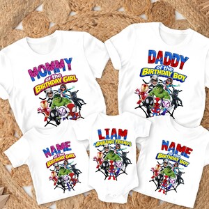 Puede incluir: Camisetas blancas con gr&aacute;ficos de superh&eacute;roes y texto. Una camiseta dice "MOMMY of the BIRTHDAY GIRL", otra dice "DADDY of the BIRTHDAY BOY". Otras camisetas dicen "NAME of the BIRTHDAY GIRL" y "NAME of the BIRTHDAY BOY". Un body dice "LIAM AMAZING FRIENDS".