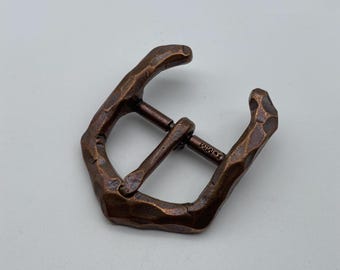 May include: A hammered copper buckle with a textured finish. The buckle is marked "18mm".
