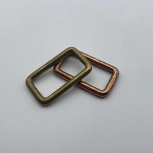 Peut inclure: Deux anneaux m&eacute;talliques, l'un en laiton et l'autre en cuivre. Les anneaux sont de forme rectangulaire et se chevauchent.