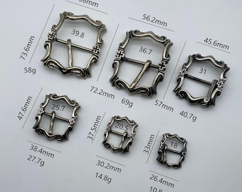 May include: Assortment of silver-toned metal belt buckles of varying sizes. The buckles are ornate with decorative details and feature a center bar with a pin and loop closure. The buckles range in size from 1.5 inches to 3 inches in width.