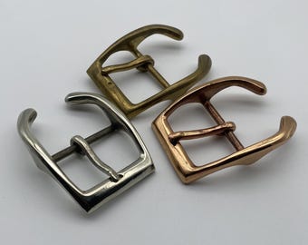May include: Three metal watch band buckles in different finishes: silver, gold, and rose gold. The buckles are all the same size and shape, with a simple, classic design.