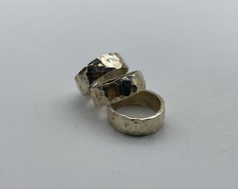 May include: Three silver rings stacked on top of each other. The rings are hammered and have a textured surface.