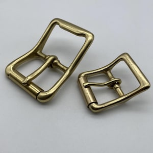 May include: Two gold-toned metal belt buckles. The buckles are rectangular with a smooth, polished finish. The buckles are designed to be used with a belt strap.