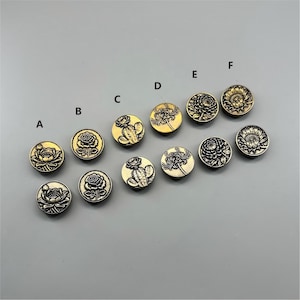 May include: A collection of round metal wax seal stamps arranged in two rows, labelled A through F. Each stamp features a distinct embossed botanical design, including roses, cacti, and various flowers, finished in antique gold and silver tones.