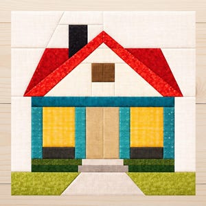 Puede incluir: Un bloque de patchwork geométrico que representa una casa. La casa tiene un tejado rojo, paredes turquesas y ventanas amarillas. Un cuadrado marrón representa una ventana y una chimenea negra es visible. La casa está sobre un césped verde con un camino blanco.
