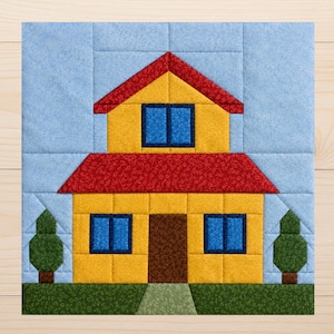 Puede incluir: Un bloque de edredón de tela cuadrado con un diseño de casa. La casa tiene paredes amarillas, un techo rojo, ventanas azul oscuro y una puerta marrón. Dos pequeños árboles verdes flanquean la casa sobre un fondo de cielo azul claro y césped.