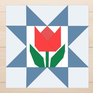 May include: A geometric quilt block design featuring a red tulip with green leaves at the centre. The tulip is surrounded by a white square, framed by blue and light blue triangles and squares. The background is a light wood grain.